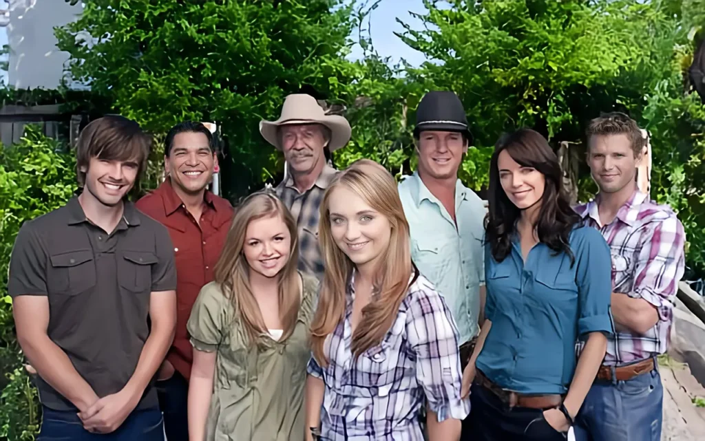 The cast of Heartland standing in front of a rustic barn